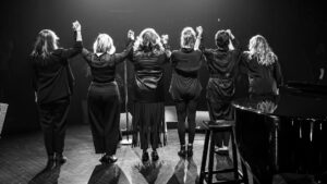 Marina Orsini sur la scène du Gesù pour la première de son spectacle Reconstruire les saisons, avec les musiciennes qui l'accompagnent, les Mommies on the run / Crédit : Rosalie-Anne Lavoie Bolduc
