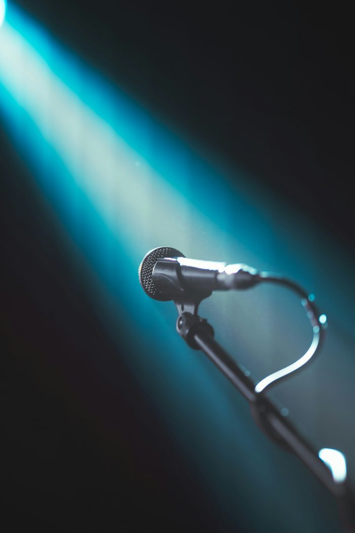 Microphone sur pied éclairé par une lumière bleue sur scène
