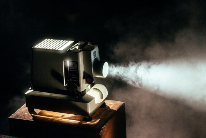 Projecteur de cinéma diffusant un faisceau lumineux dans une salle sombre avec de la fumée visible